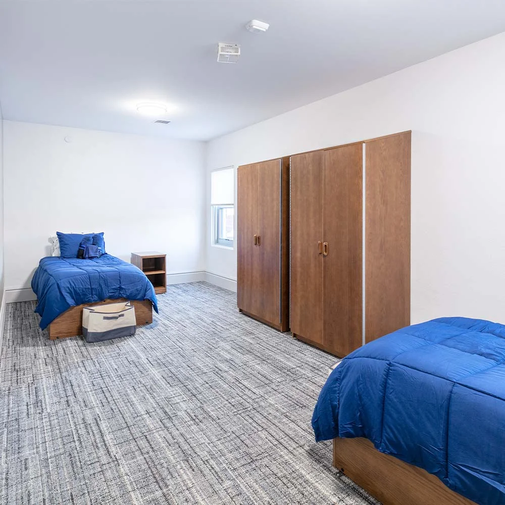 Two twin beds with blue bedding and wardrobes
