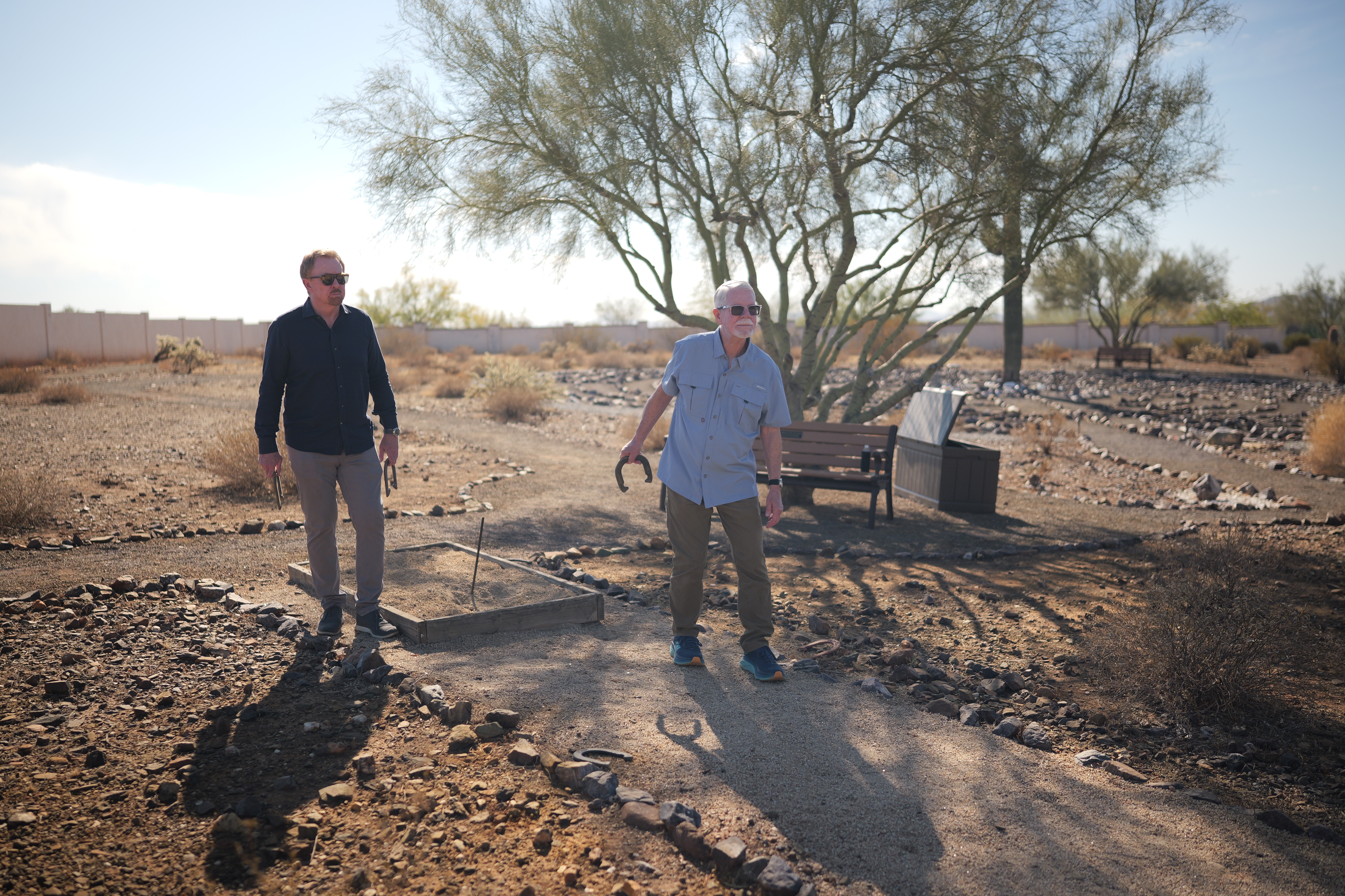 Two men playing horseshoes in a desert garden setting