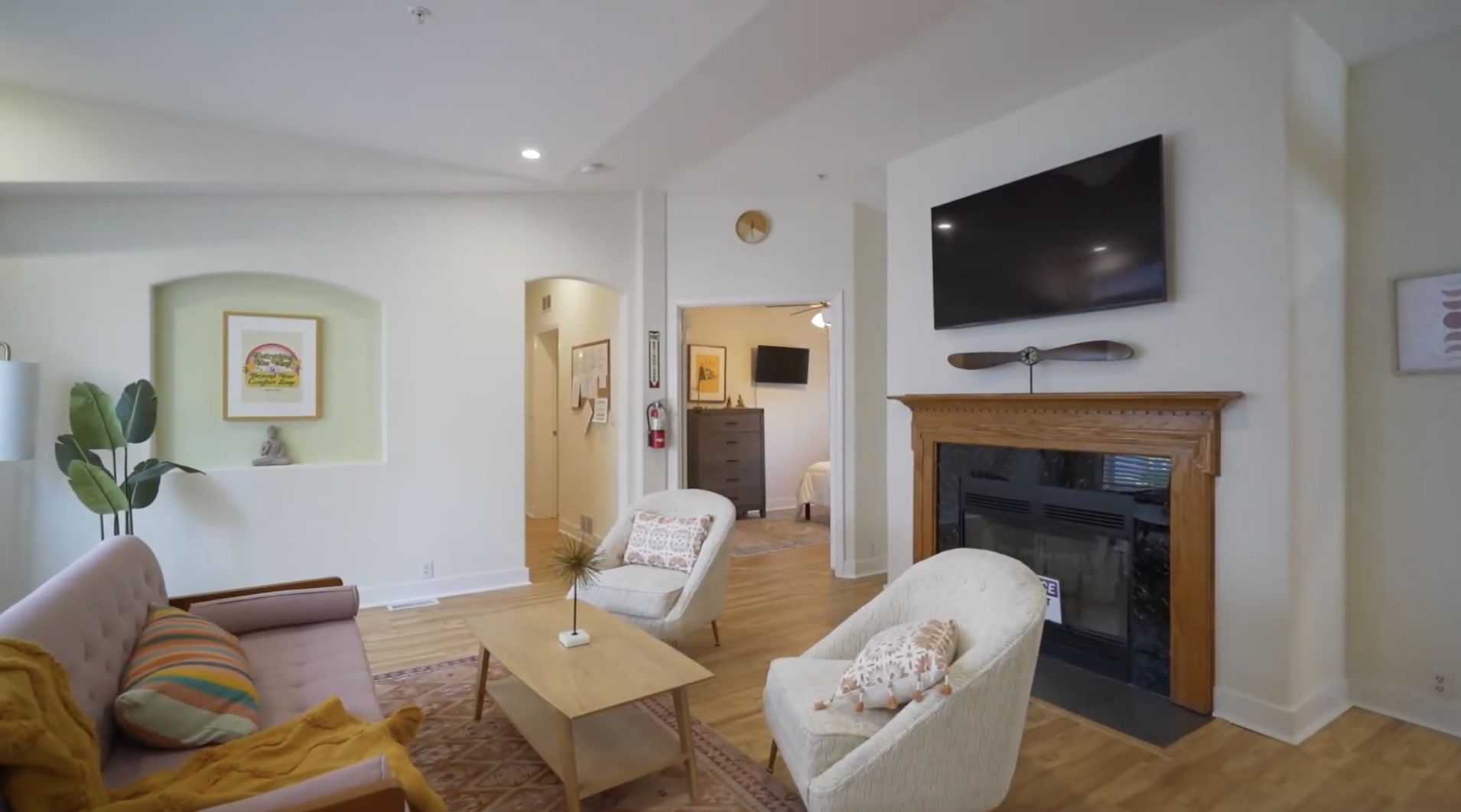 Living room with sofa, armchairs, fireplace, and wall-mounted TV