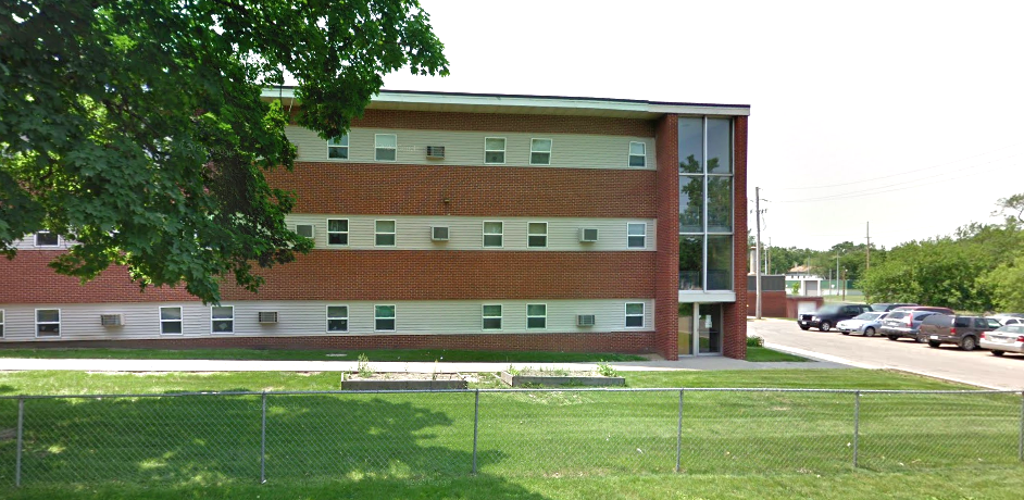Brick residential facility with large windows and side parking lot