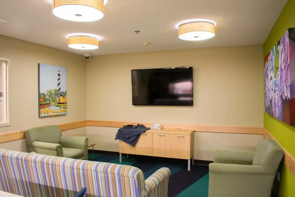 Cozy lounge with striped sofa, green chairs, and wall-mounted TV