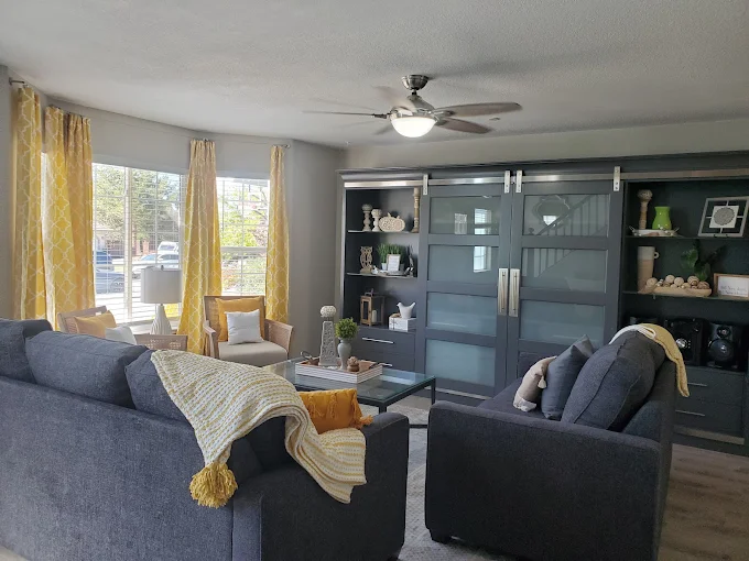 Bright lounge with gray sofas, yellow accents, and large window