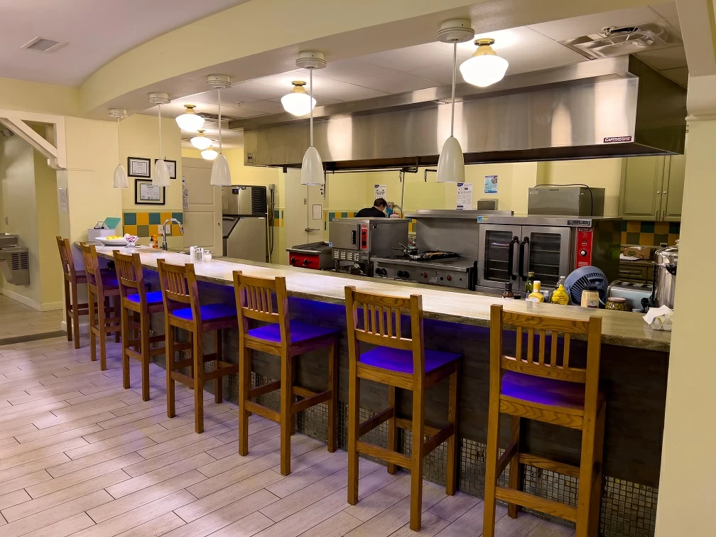 Commercial kitchen with bar seating, stainless steel appliances, and preparation area at treatment facility