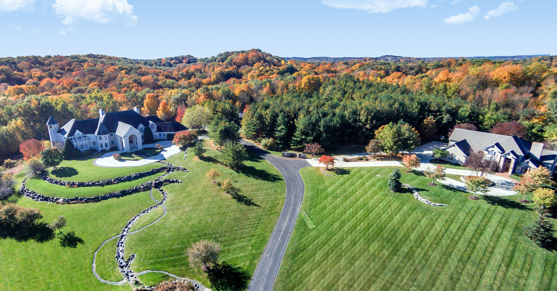 Aerial view of large estate with landscaped lawns and autumn trees.