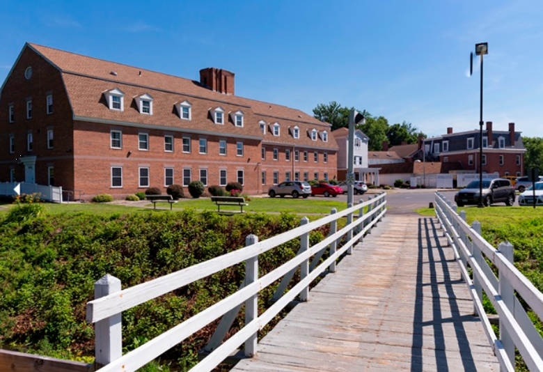 Brick rehab facility with white footbridge on sunny day