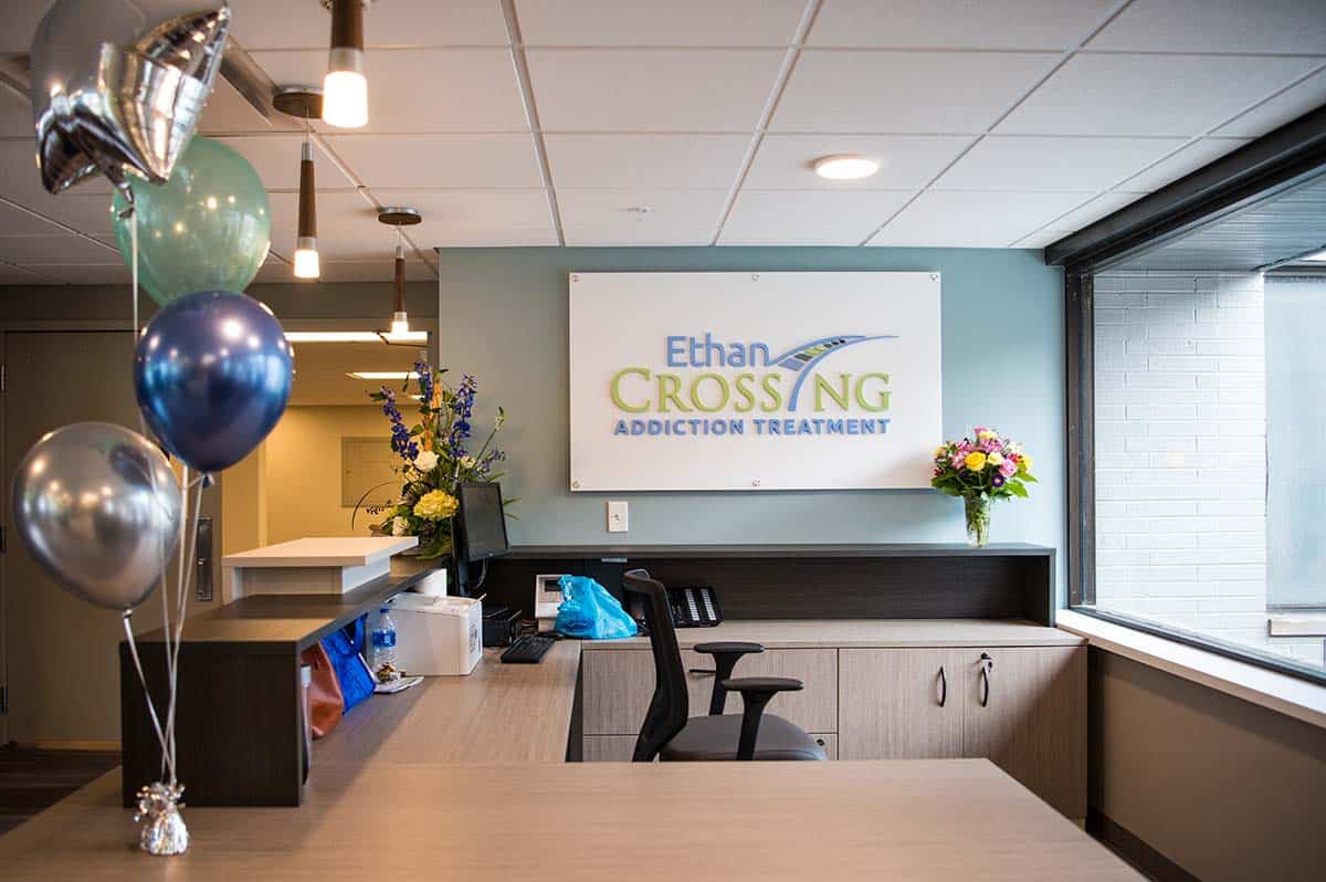 A reception desk with balloons and an "Ethan Crossing" sign.