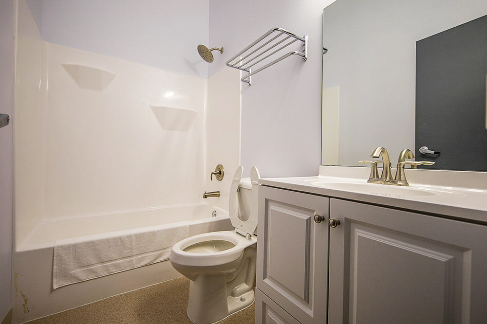 A clean bathroom with a white sink, toilet, and bathtub with a shower.