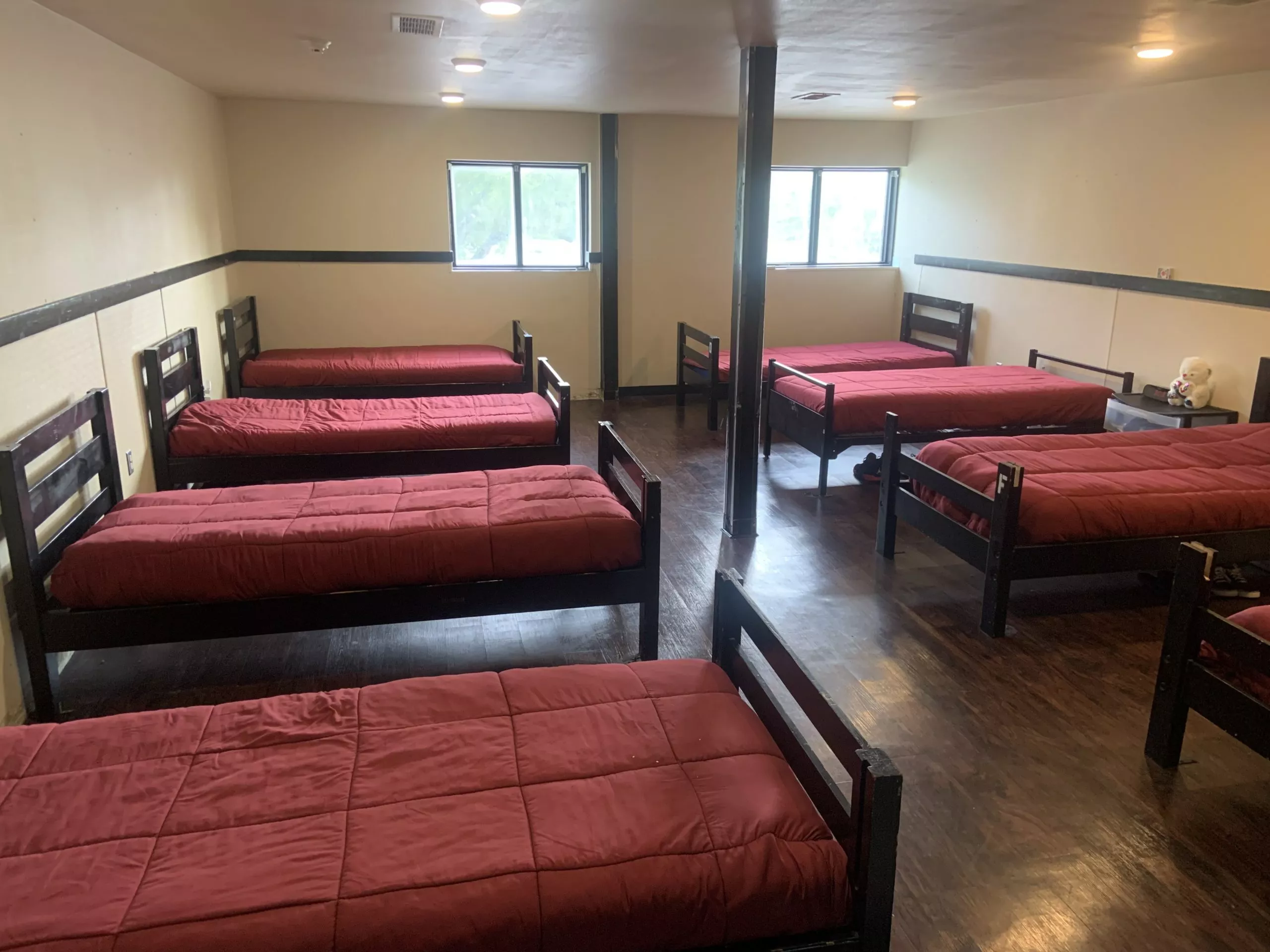 Dorm-style room with eight single beds and maroon bedding