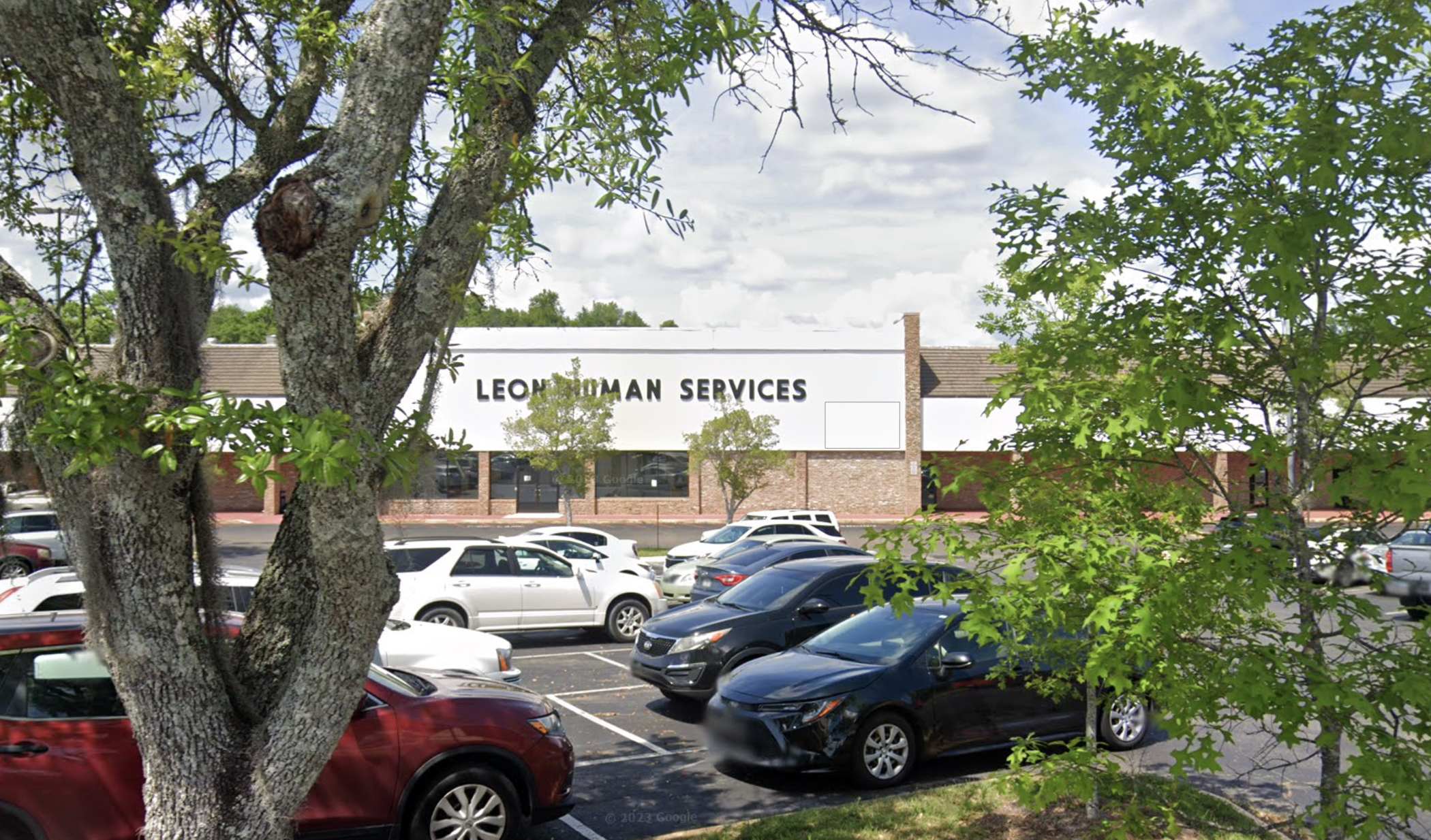Front of Leon Adult Services building behind trees and parking lot