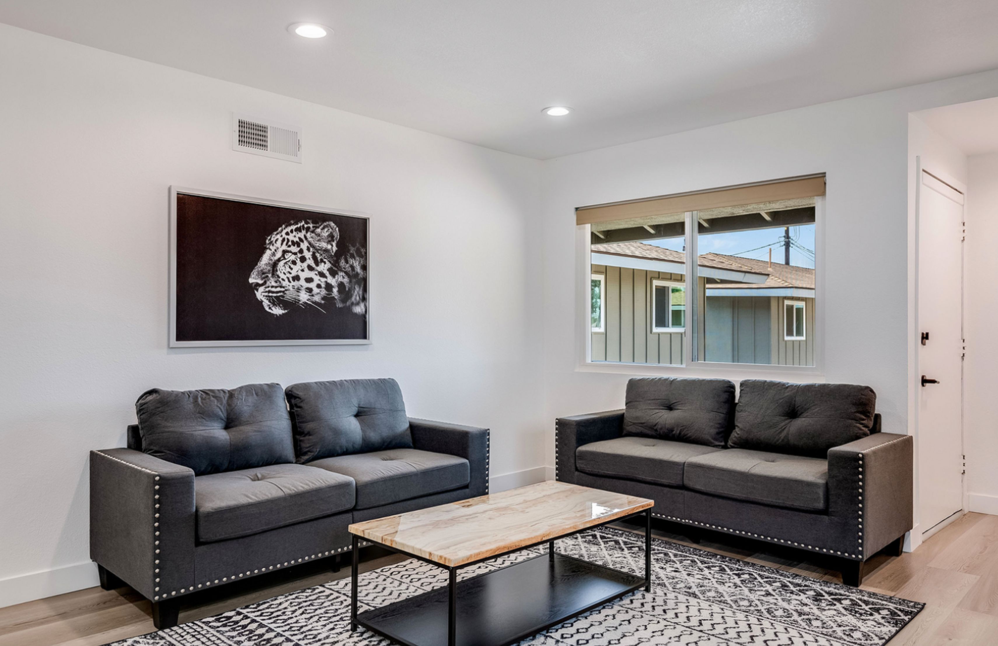Modern living room with dark sofas and leopard artwork.