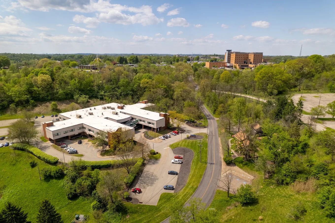 Aerial view of the facility, parking areas, and wooded grounds