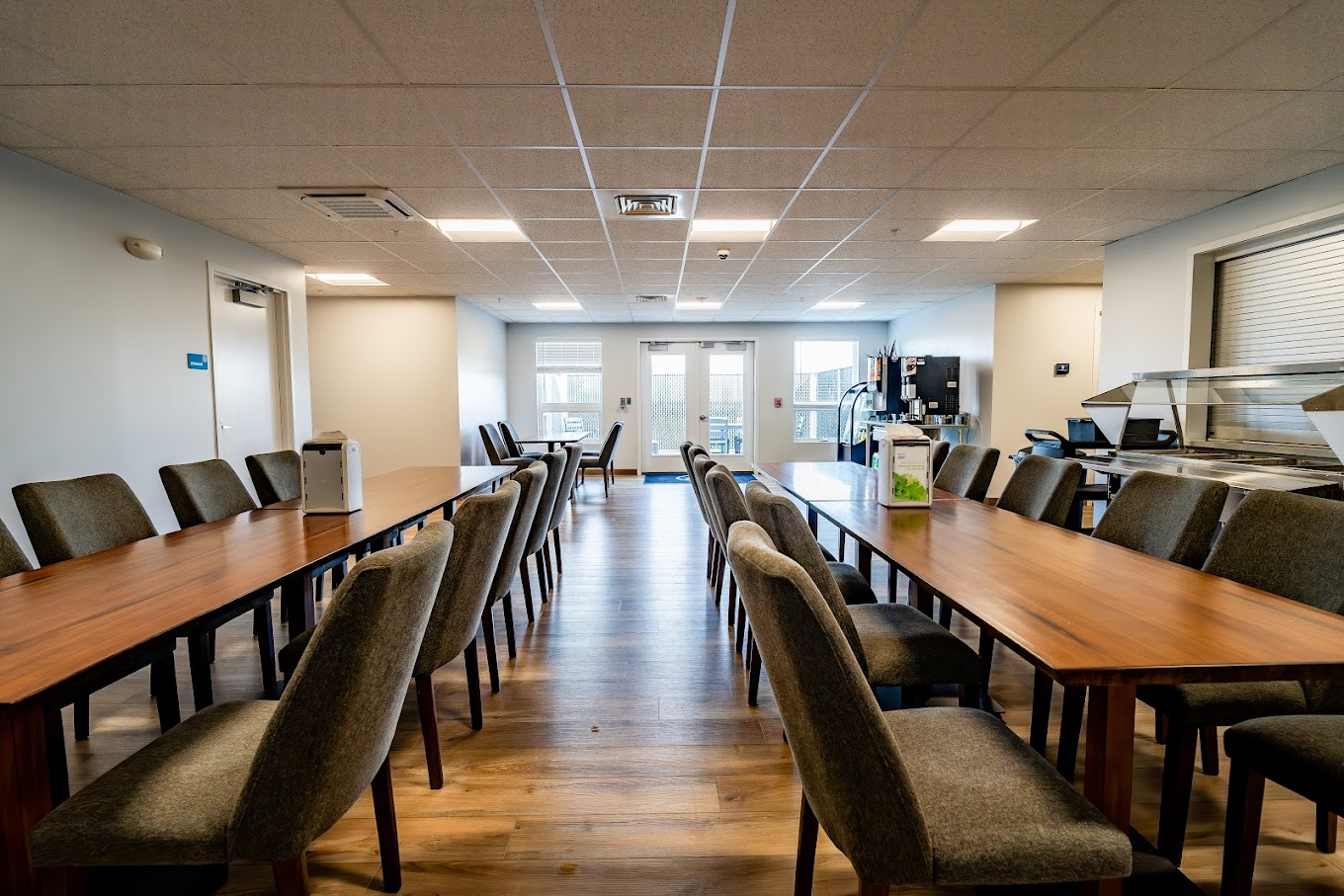 Dining area with long wooden tables and upholstered chairs.