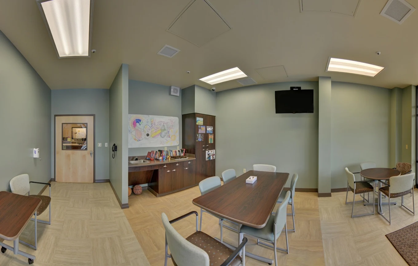 Multi-purpose room with tables, chairs, and art wall