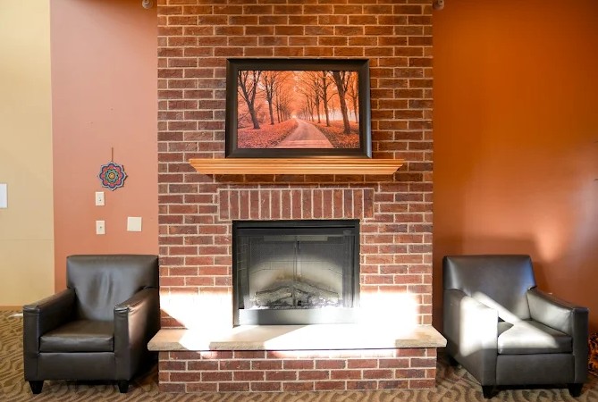 Cozy lounge with brick fireplace and two leather chairs