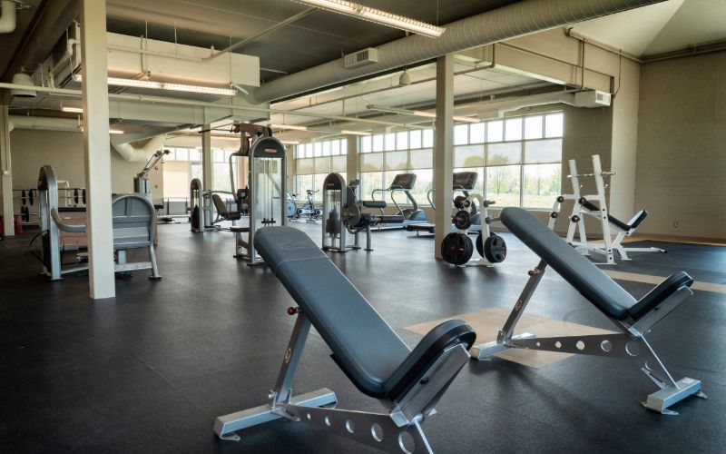 Home gym with Peloton, treadmill, benches, and free weights