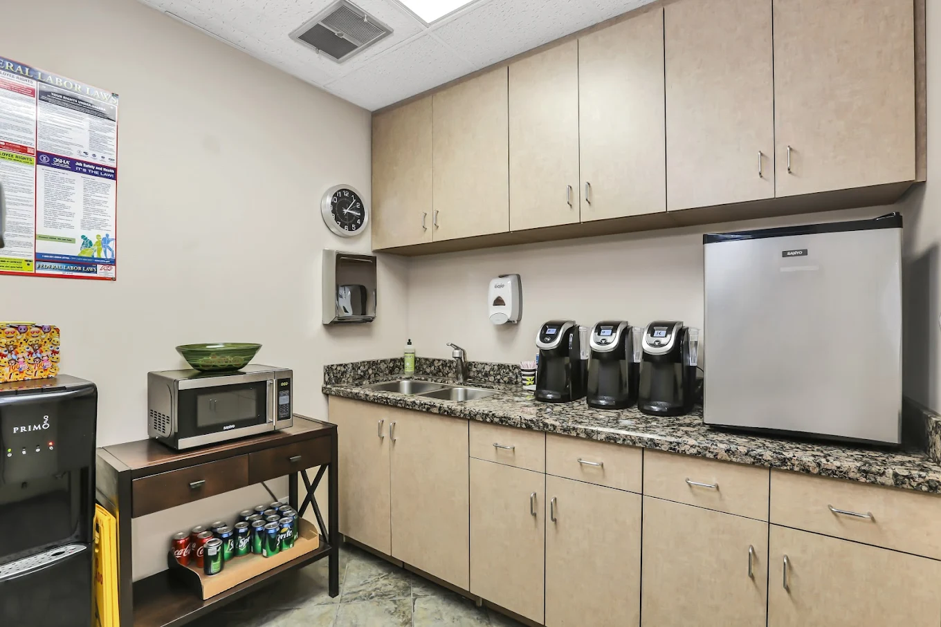 Compact kitchen space with coffee makers, fridge, microwave, and beverage station