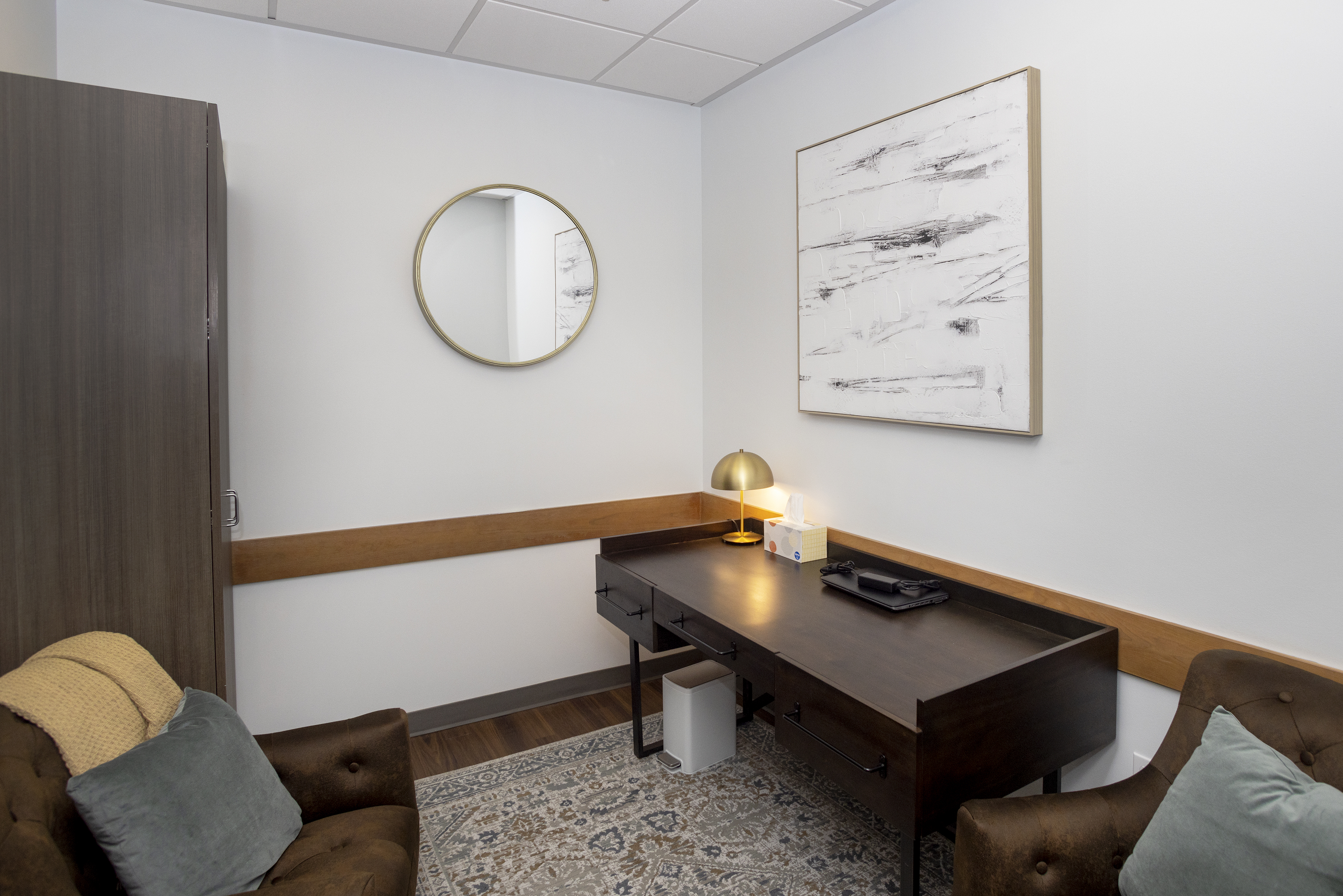 Office with brown chairs, desk, and abstract art