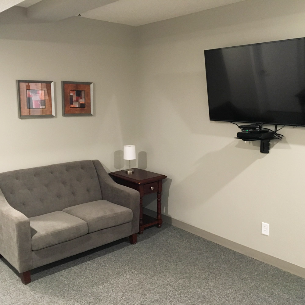 Gray loveseat and mounted TV with framed wall art