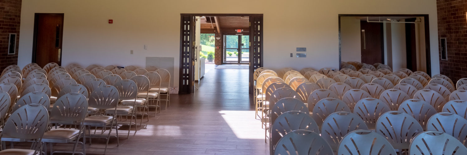 Rows of chairs facing open door in sunlit church room