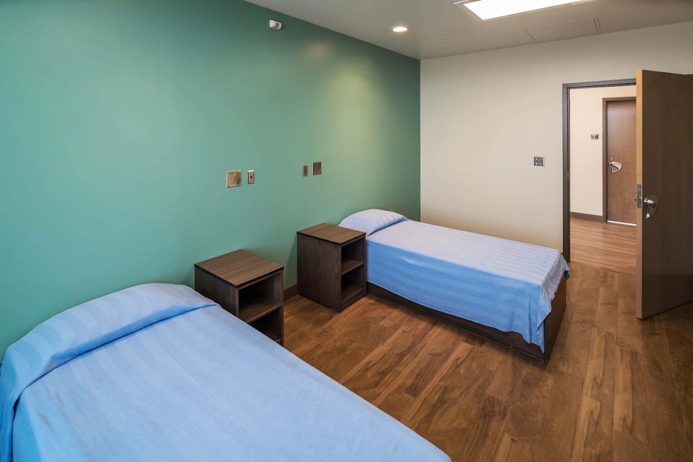 Shared patient bedroom with two beds and bedside tables.