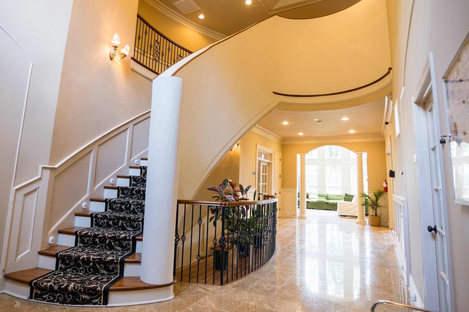  A grand staircase with an ornate railing inside a well-lit foyer