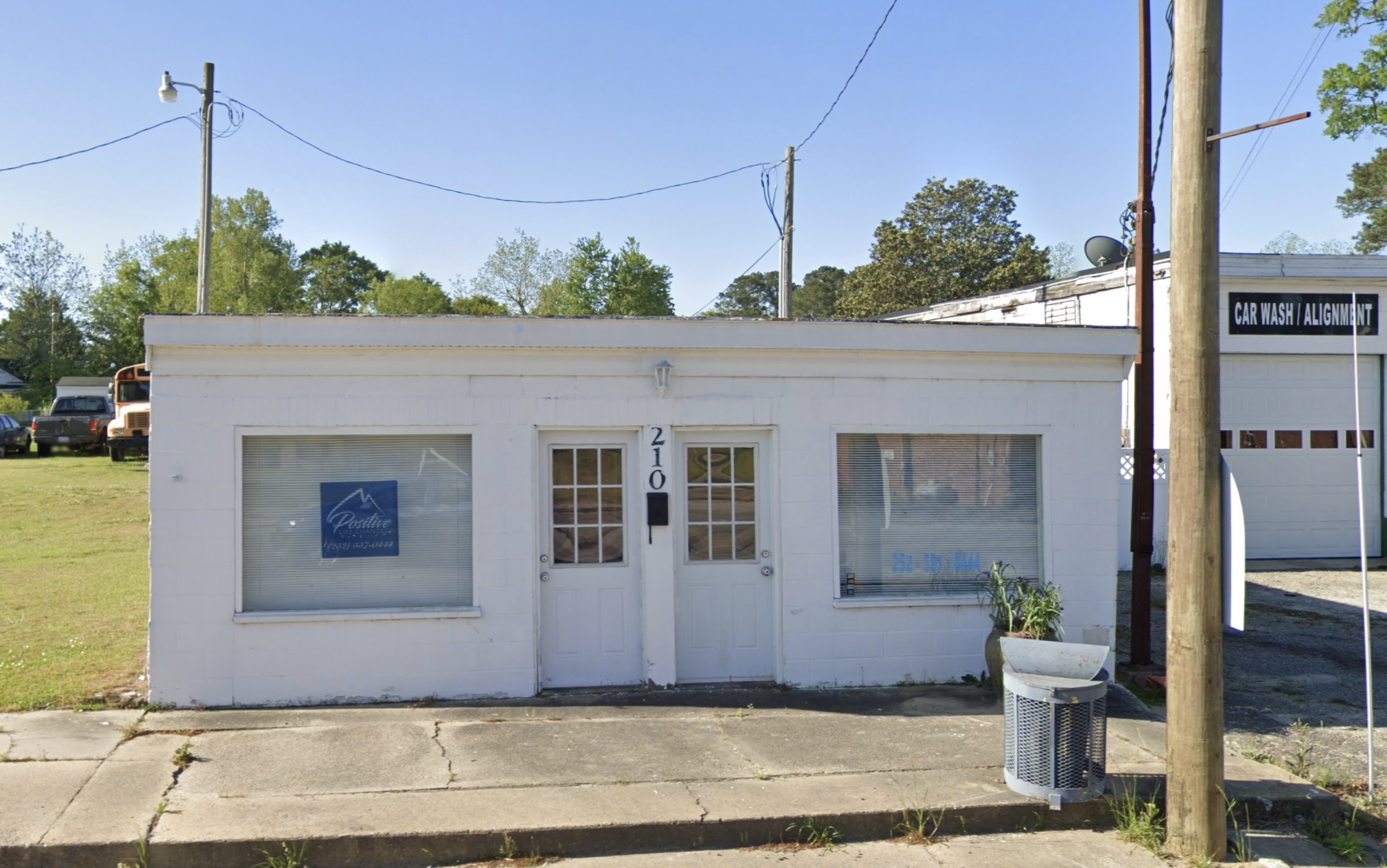 Front of PLC with large front windows and a clean, simple exterior. The entrance is marked by two white doors.