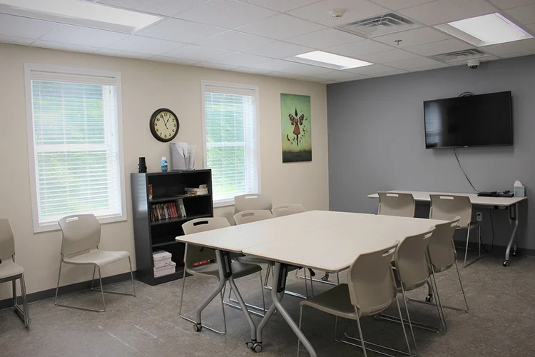 Therapy room with tables, chairs, and wall TV