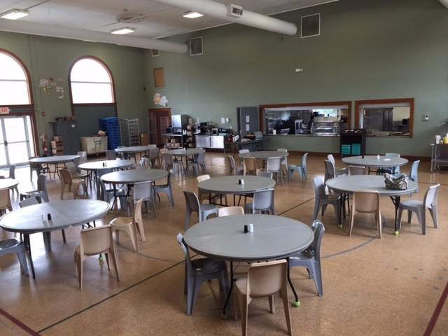 Large rehab dining room with gray chairs and round tables