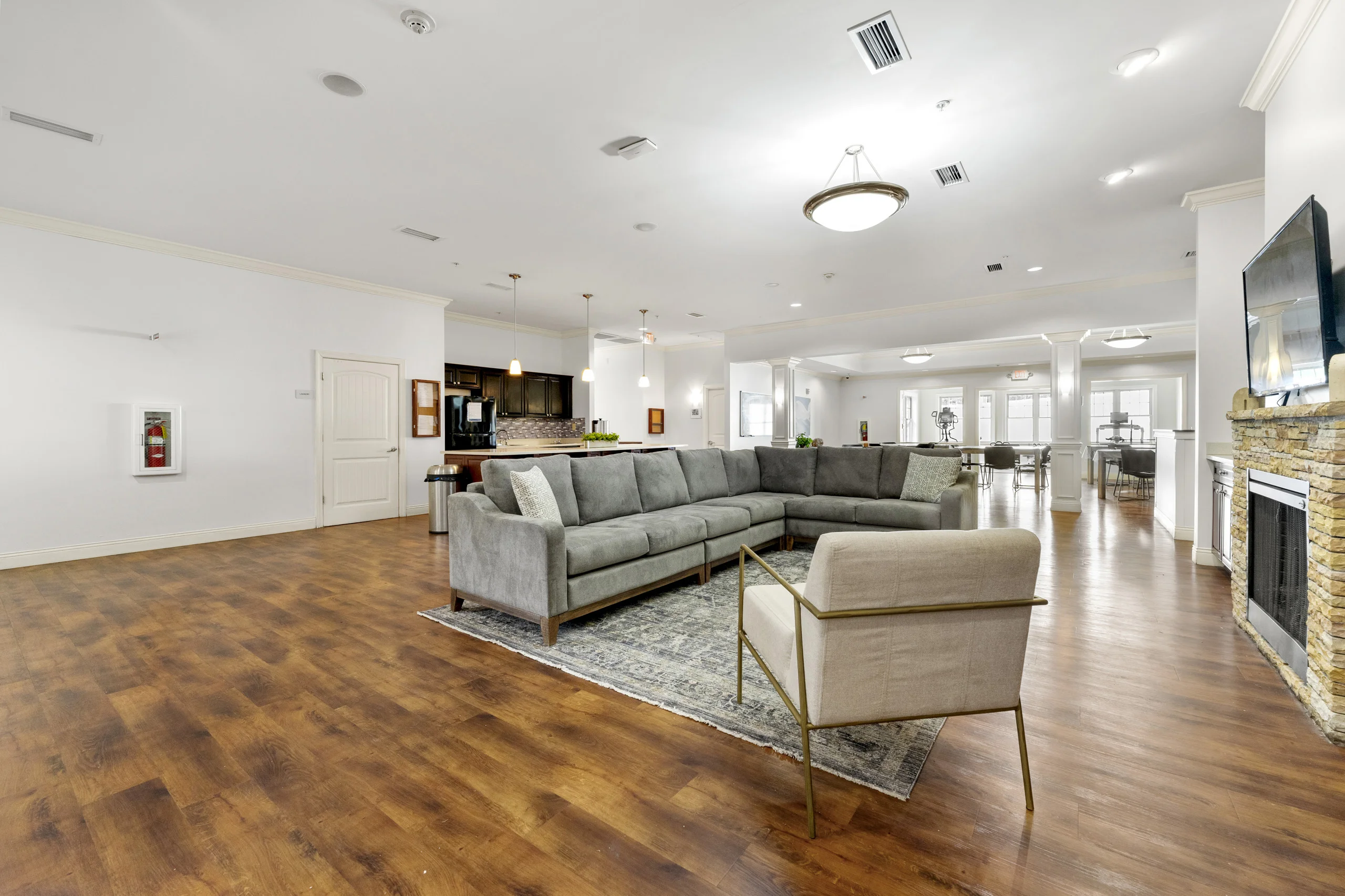Spacious community lounge with comfortable seating, fireplace, television, and open gathering area for residents