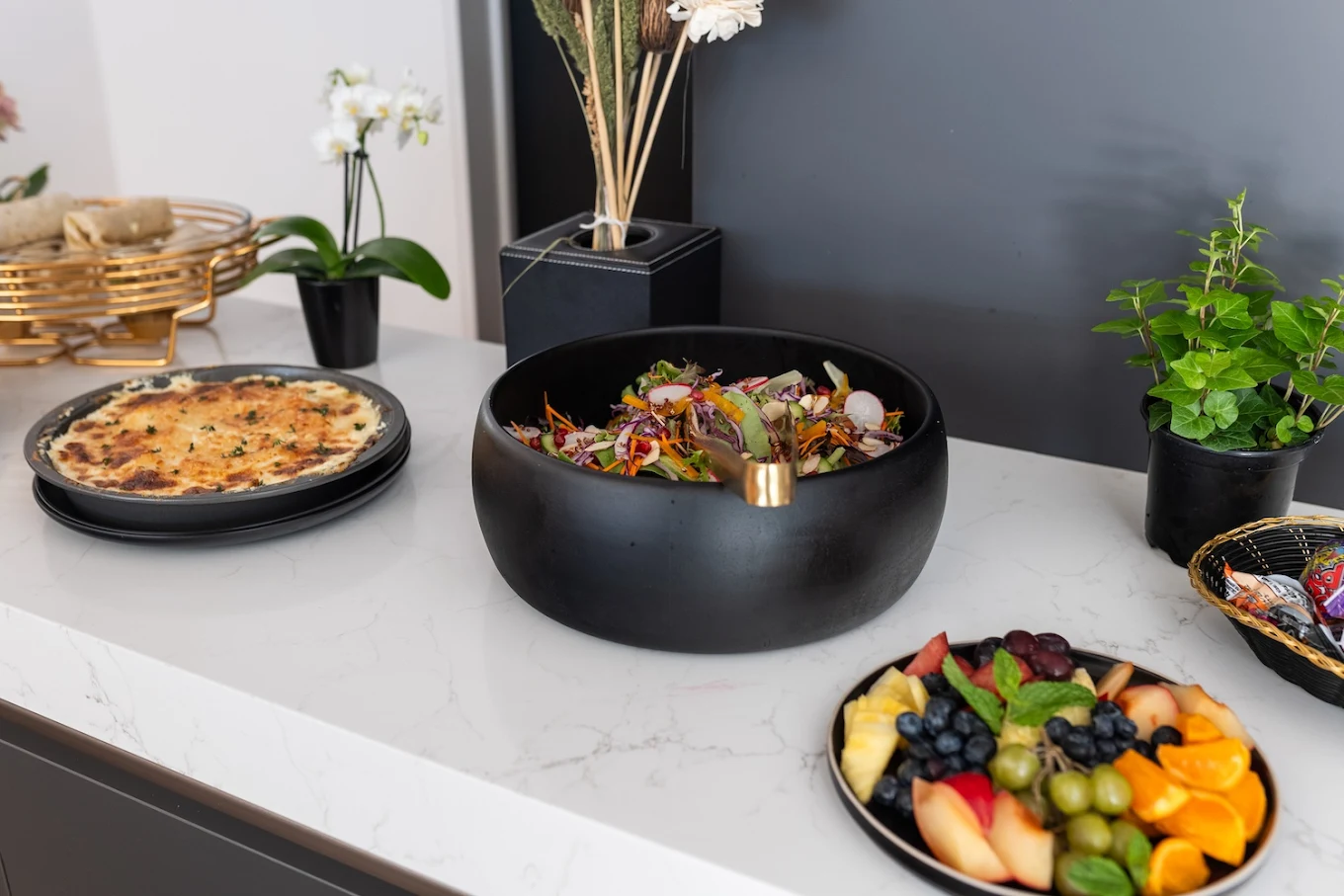 Fresh salad, fruit platter, and baked dish on counter