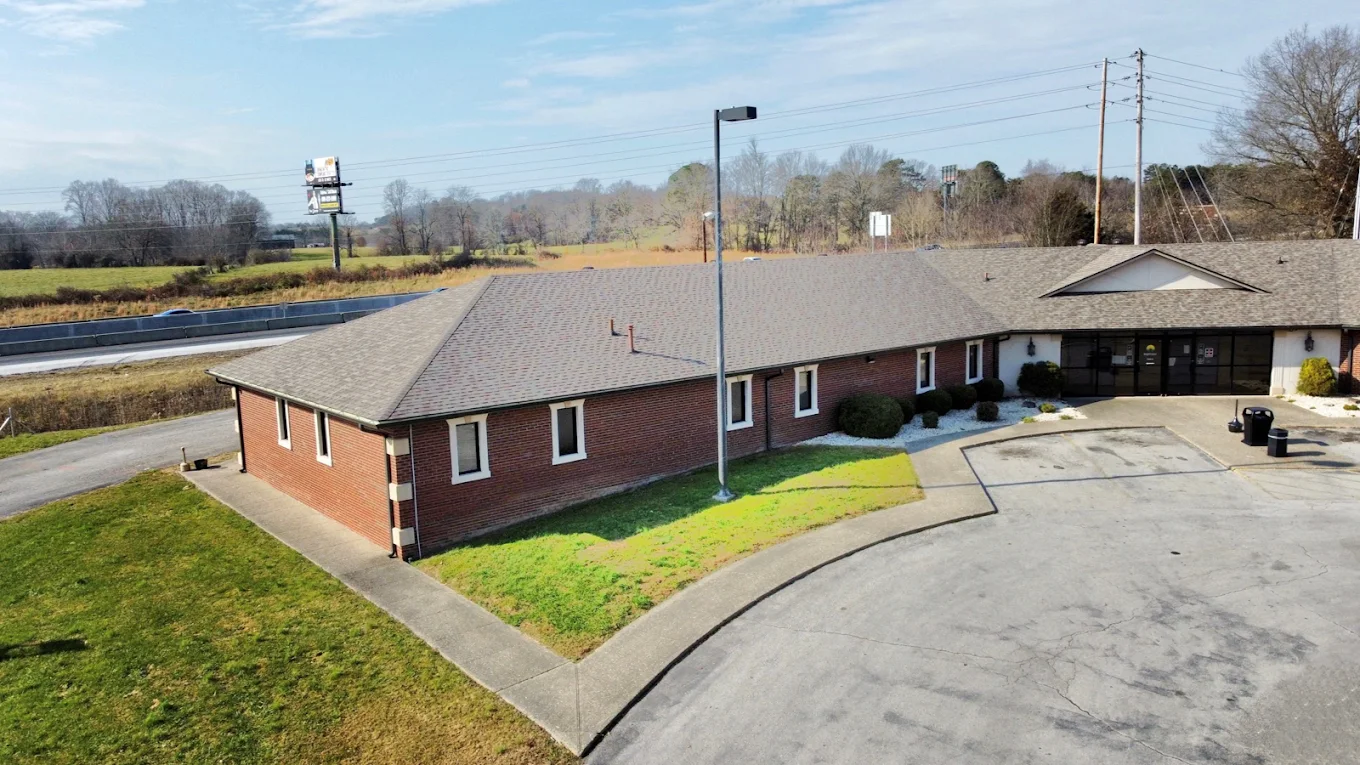 Elevated exterior view of the BrightView Health London brick treatment center showing the main entrance, paved driveway, landscaped grounds, and nearby roadway