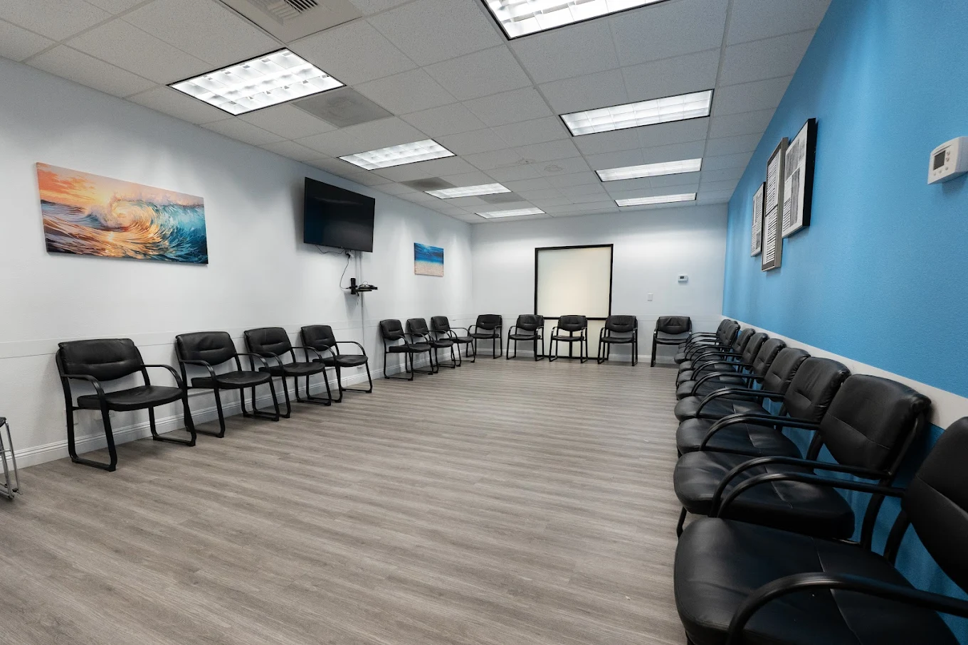 Therapy room with rows of black chairs and wall art