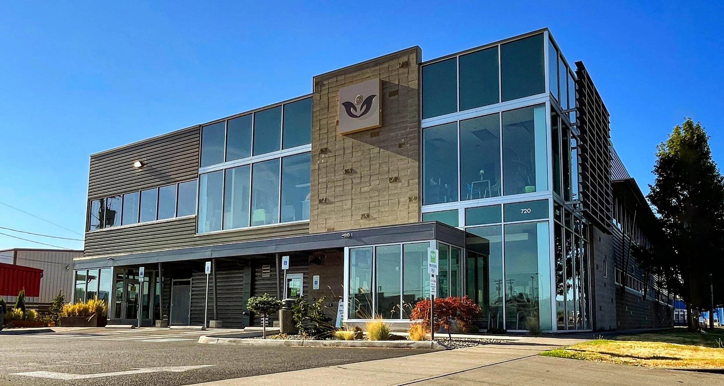 Modern glass-front rehab facility under clear blue sky