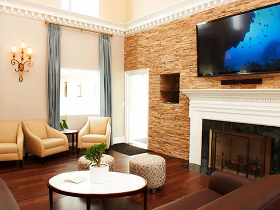 Lounge with beige chairs, fireplace, and wall-mounted TV