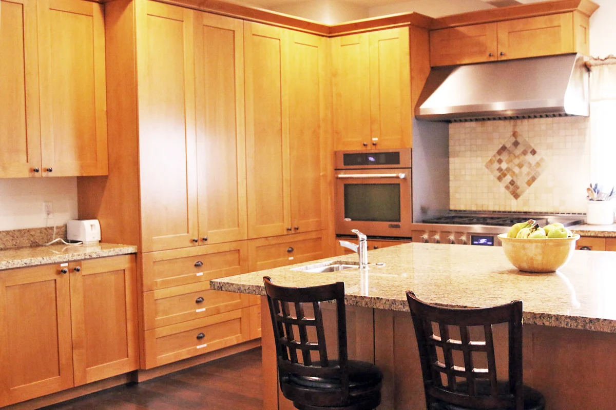 Spacious kitchen with wooden cabinets and granite island