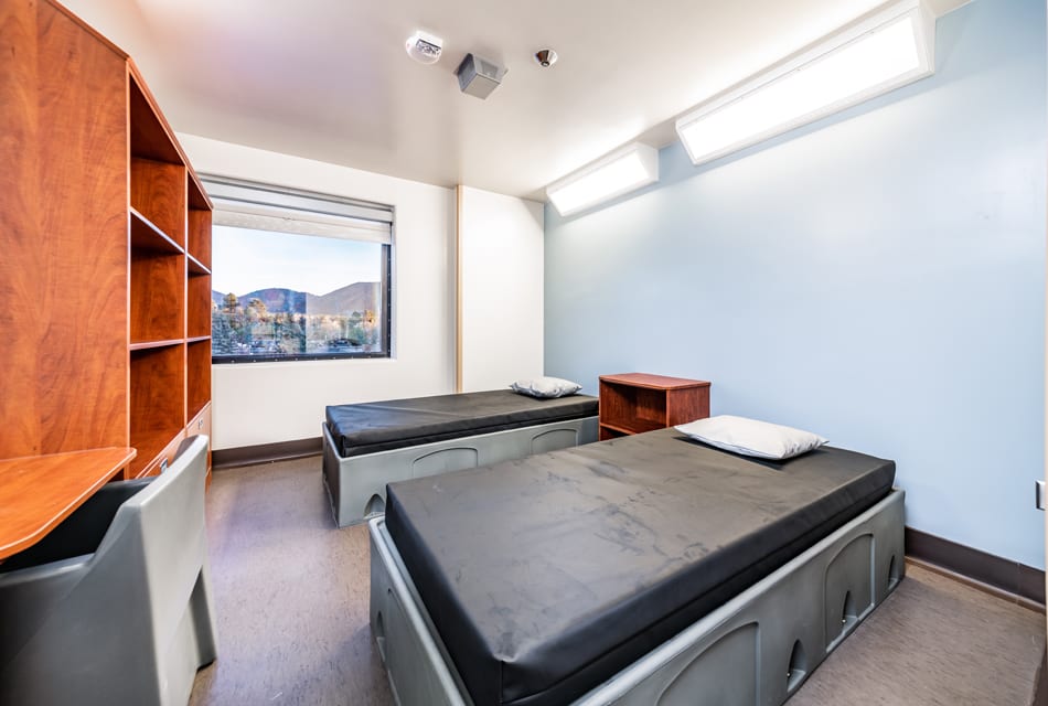 Twin beds with desks and window view of the mountains