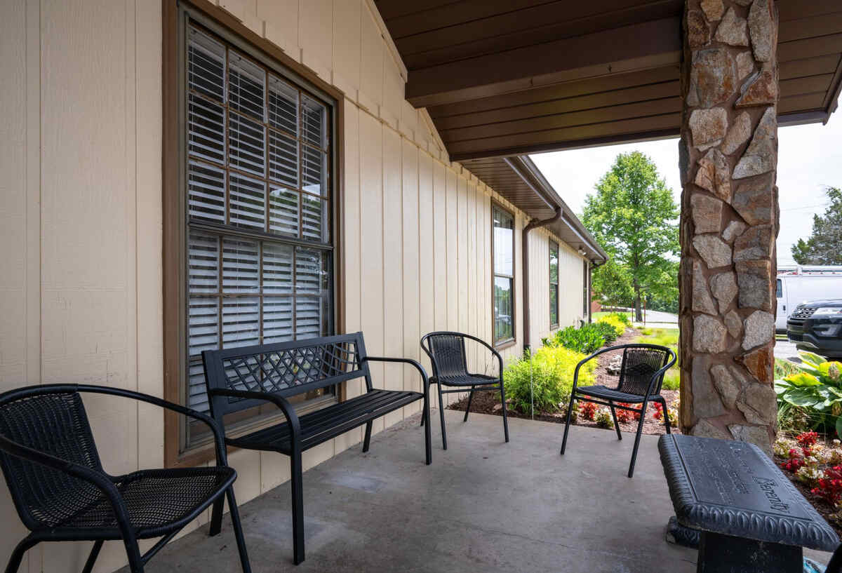 Covered outdoor seating area with black chairs and a stone column.