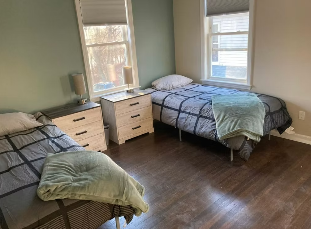 Shared bedroom with two beds, dressers, and natural light