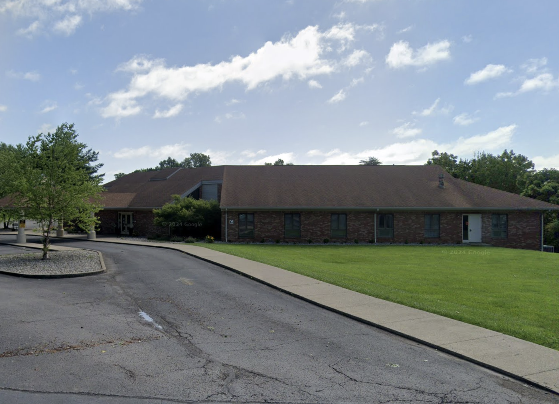 Single-story brick building with a sloped roof and green lawn