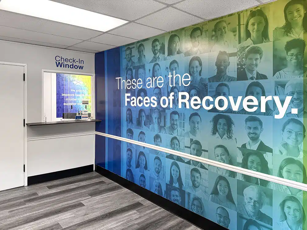 Hallway check-in window with faces of recovery mural