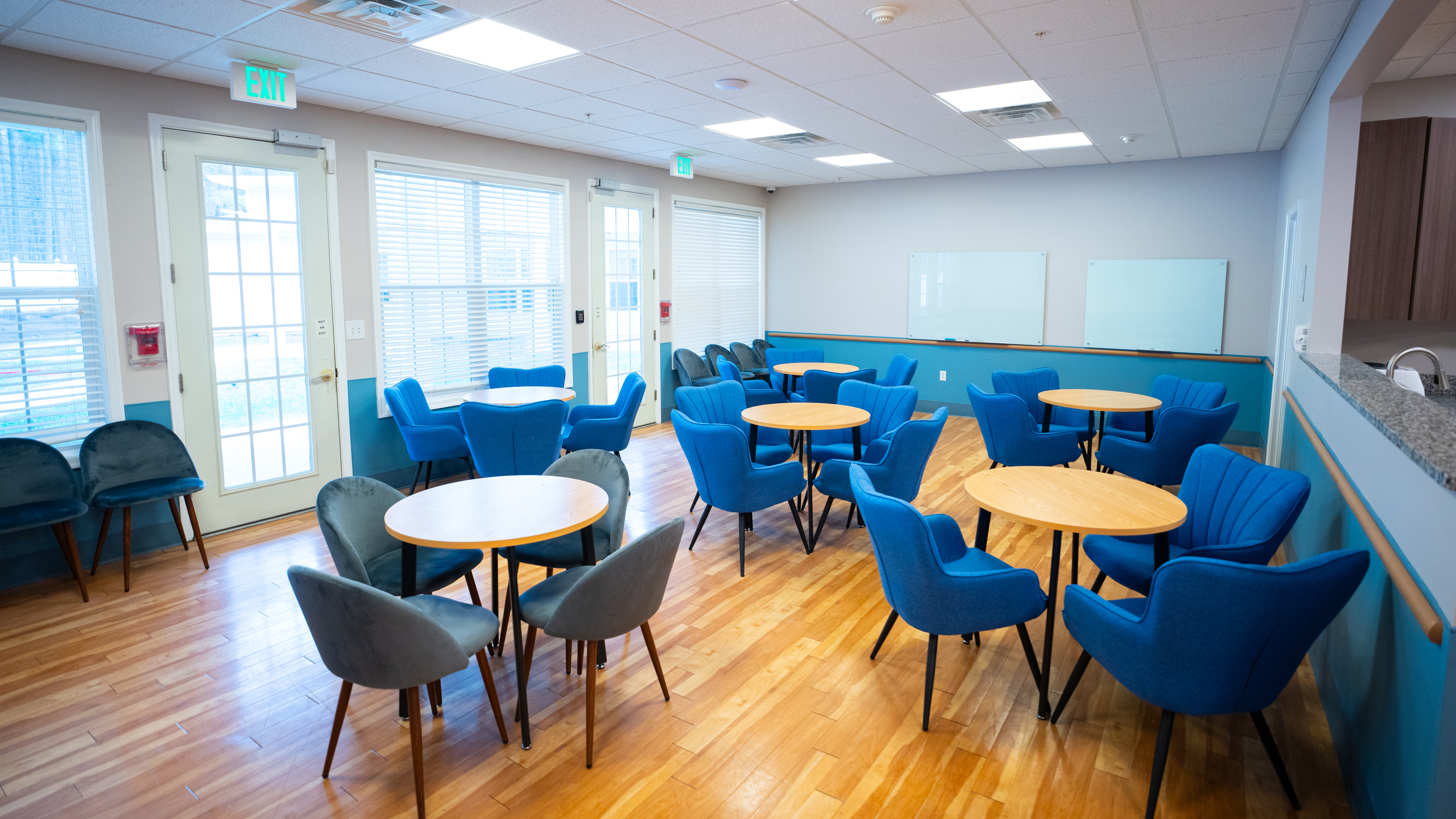 Bright group room with blue chairs and round tables