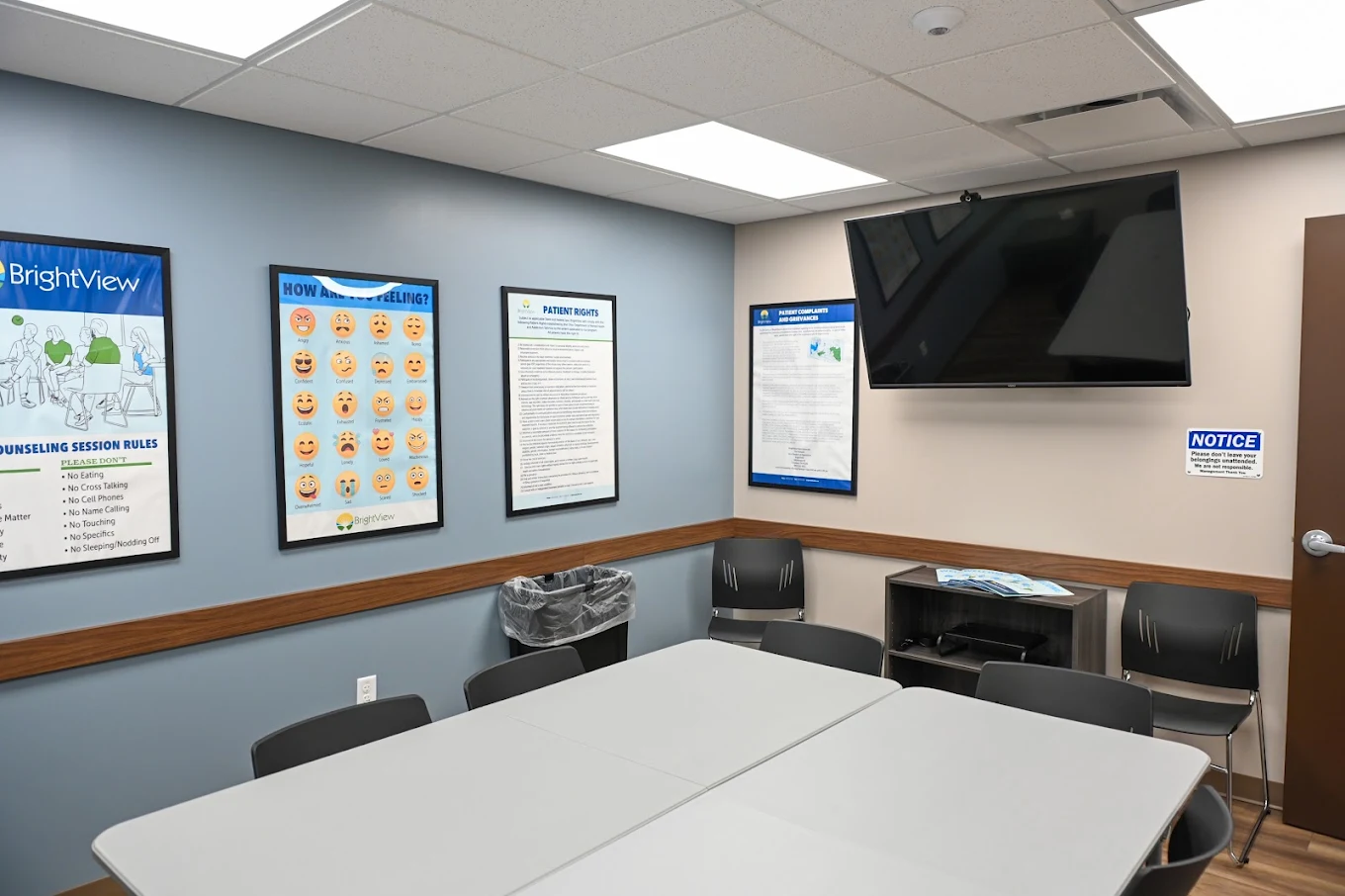 Group therapy room with tables, chairs, and TV