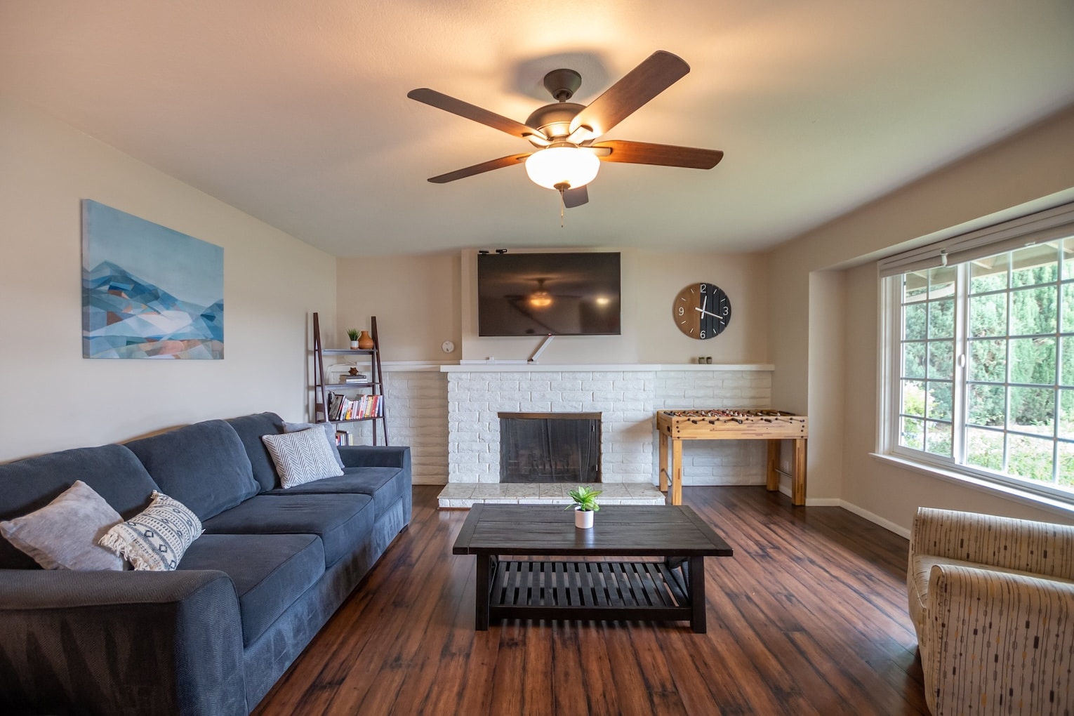 A living space with a fireplace, sofa, and foosball table.