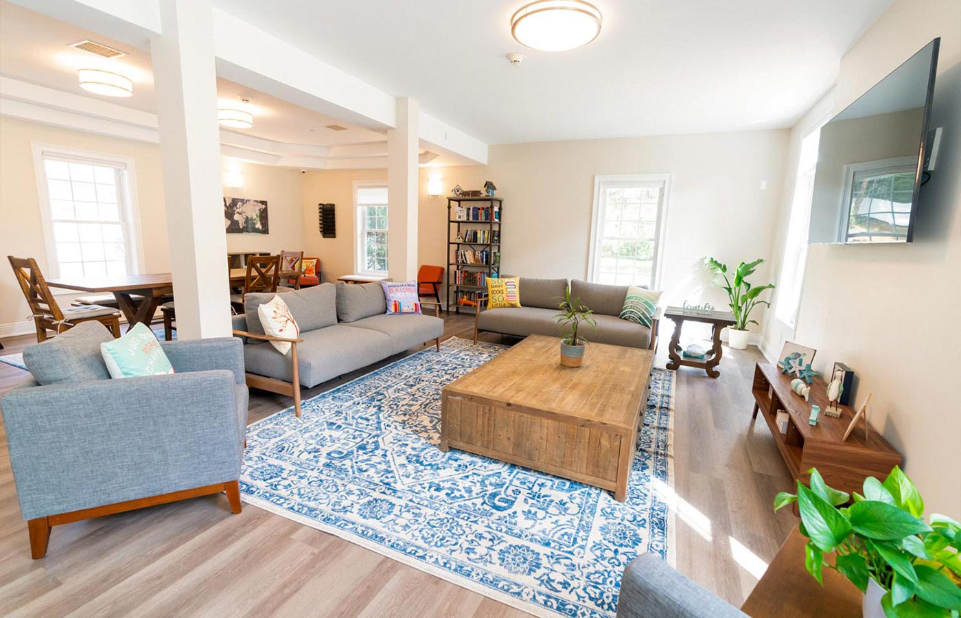 Bright shared living room with couches, tables, and natural light.