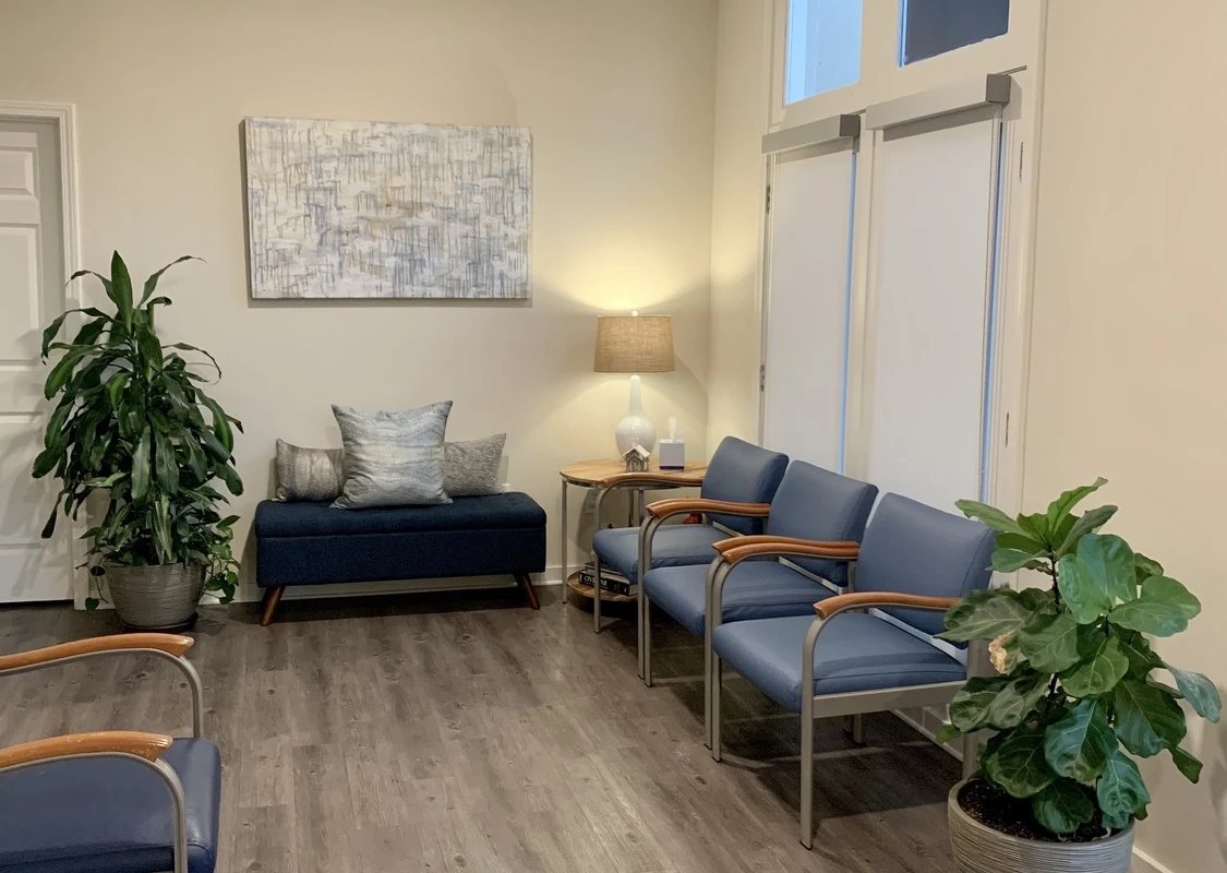 Blue chairs and bench with pillows, lamp, and indoor plants