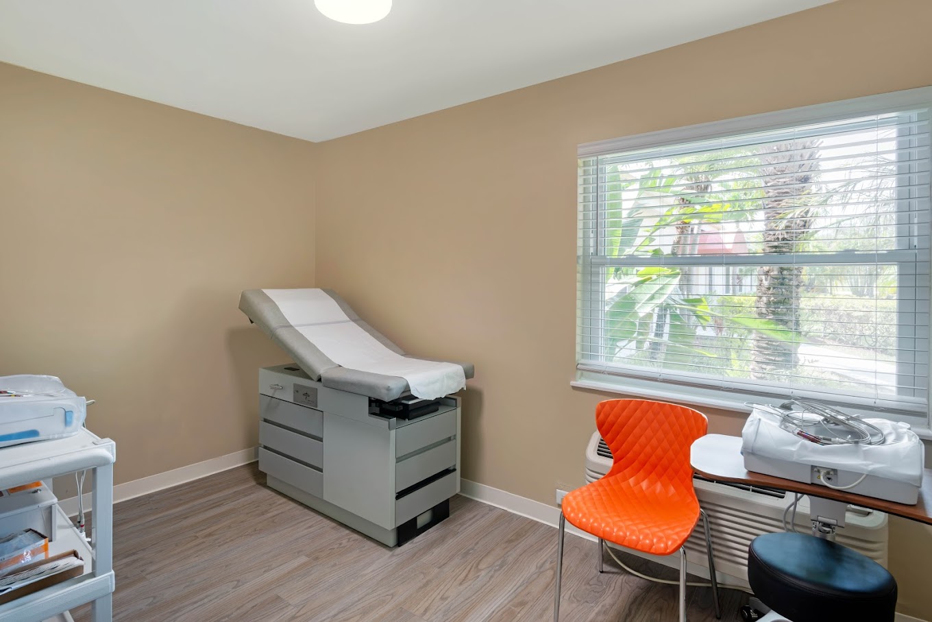 A medical examination room eith exam table, and chair.