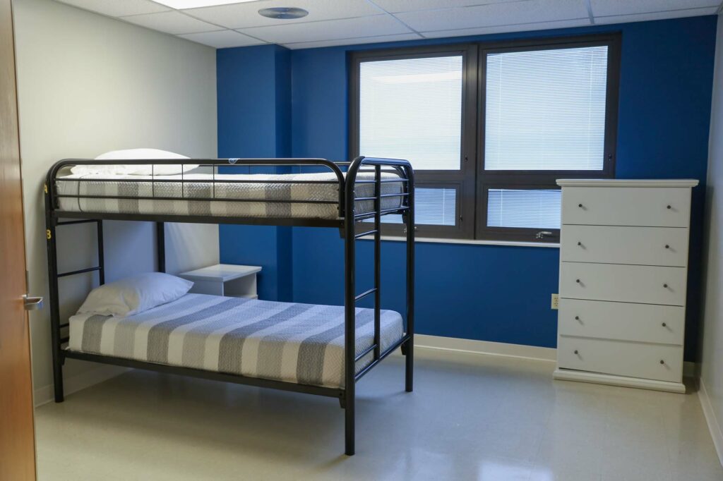 Bedroom with metal bunk bed and dresser by window