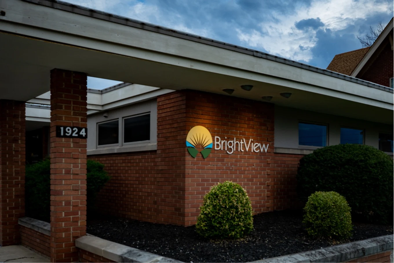 Brick BrightView building entrance with landscaped shrubs