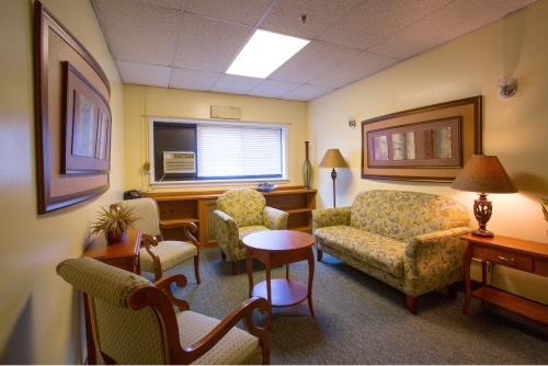 A cozy lounge with a sofa, armchairs, and wooden furniture.