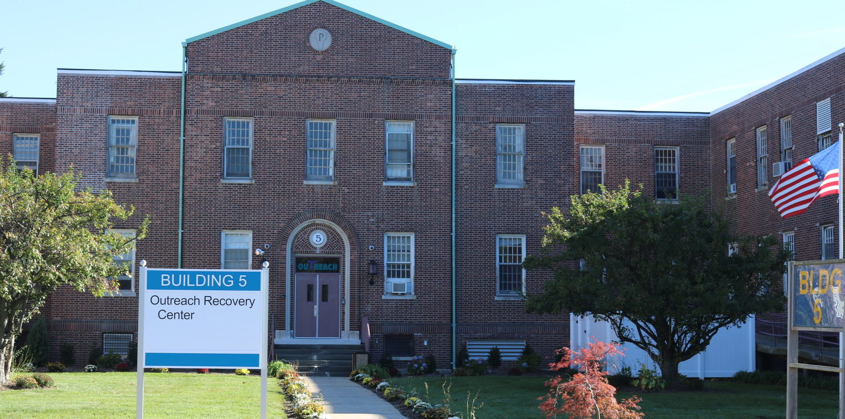 Brick rehab facility with entrance sign and landscaped front lawn
